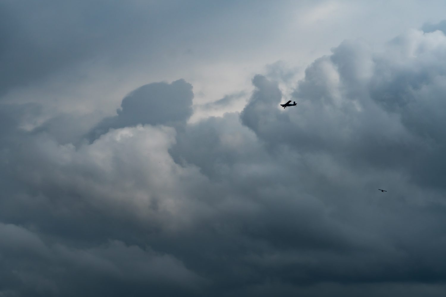 Piccolo aereo nel cielo nuvoloso per la produzione di pioggia.  Nuvole bianche e soffici con piccoli aerei per produrre piogge artificiali.  Due aerei che volano sul cielo nuvoloso.  Aereo agricolo per precipitazioni artificiali.