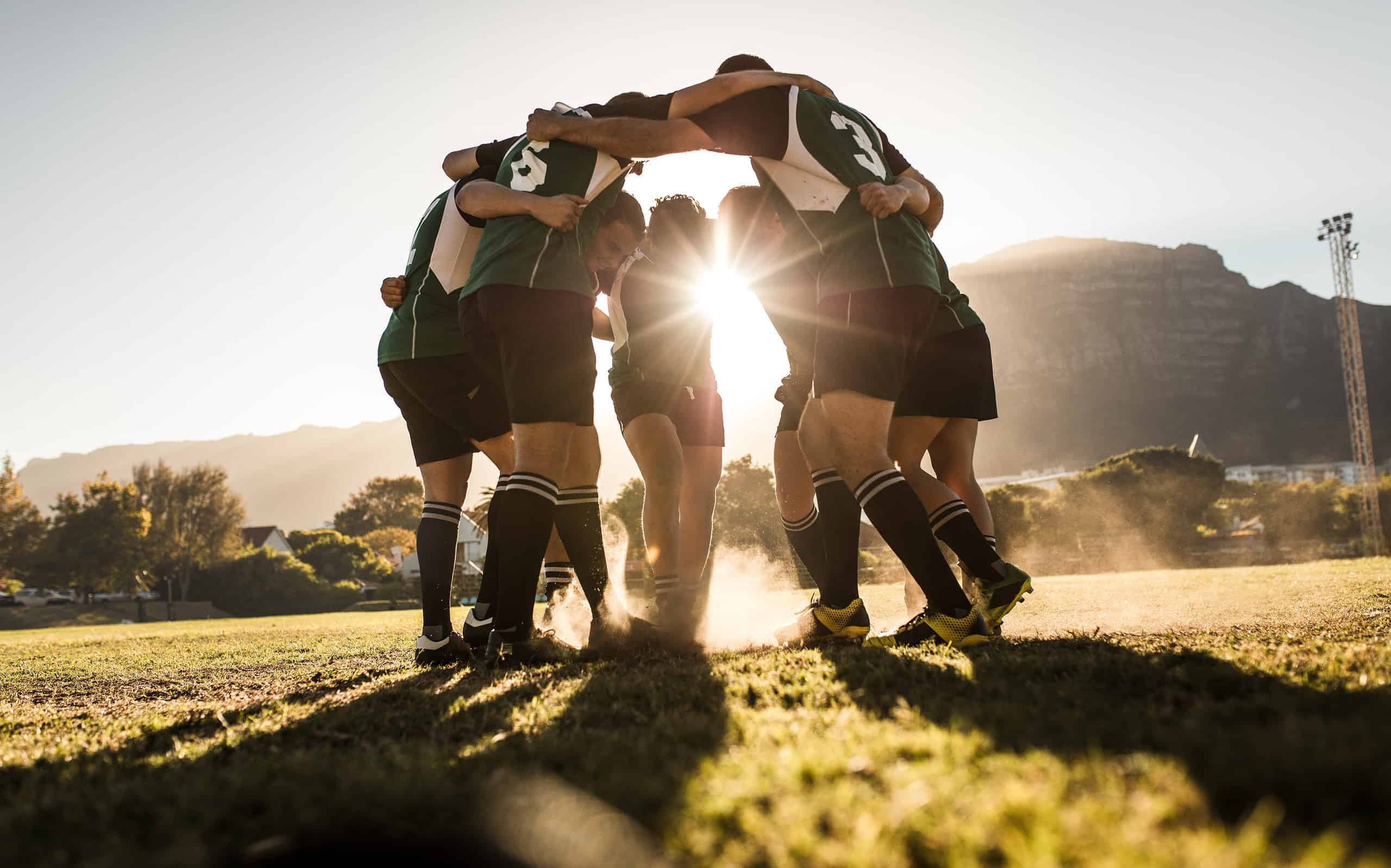 Squadra di rugby in piedi in una calca e strofinando i piedi a terra.  Squadra di rugby che celebra la vittoria.