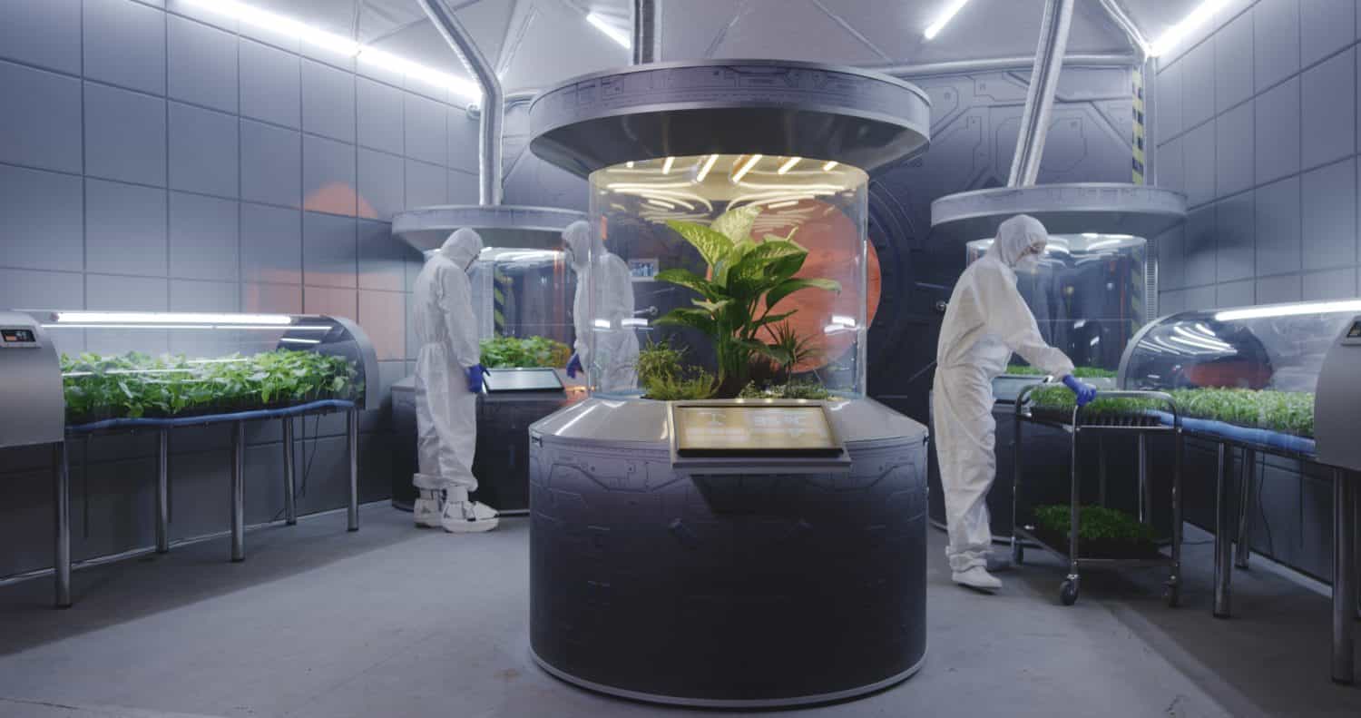 Inquadratura completa di scienziati in tute ignifughe che controllano gli incubatori di piante su una base su Marte