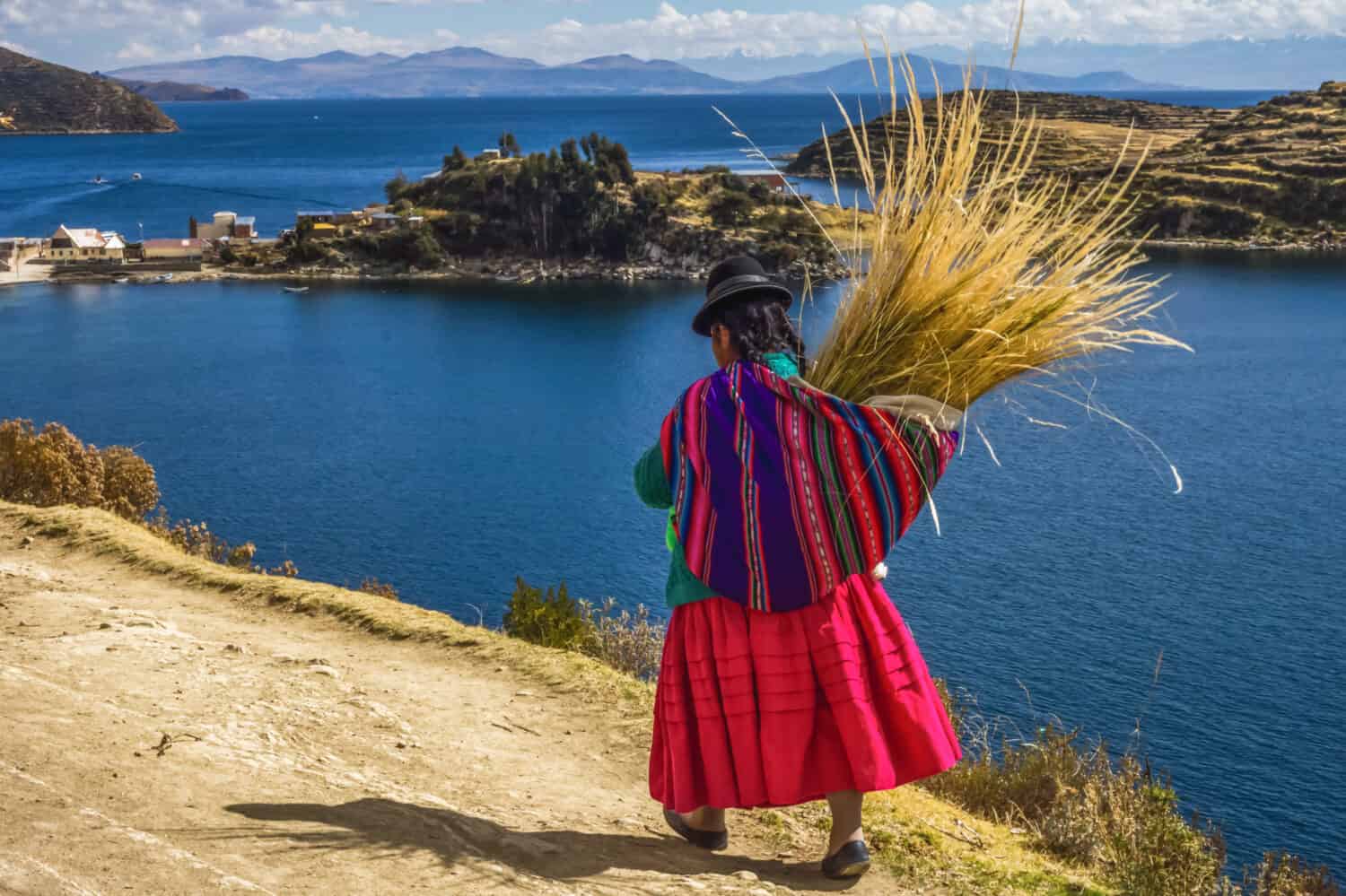 Donna boliviana tradizionale in abito tradizionale, camminando attraverso l'isola del sole nel lago titicaca, Bolivia