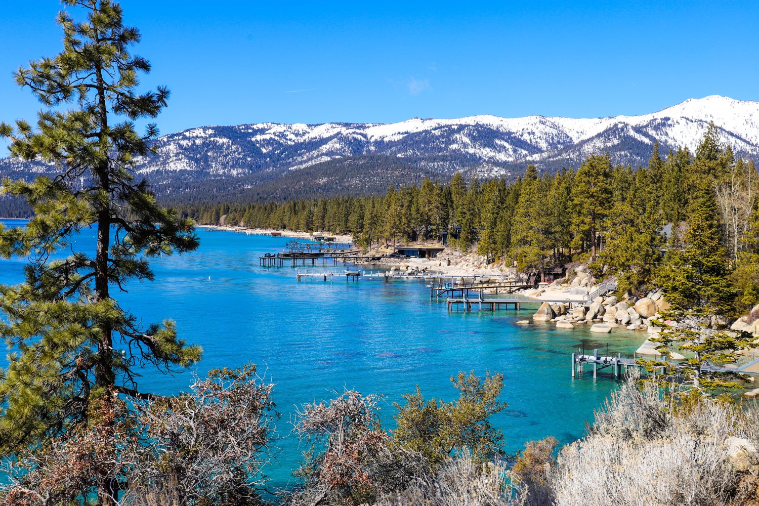 uno splendido paesaggio invernale con acque cristalline del lago, catene montuose innevate e rigogliosi alberi verdi lungo le rive del lago e cielo azzurro al Lake Tahoe nel Nevada State Park a Incline Village	