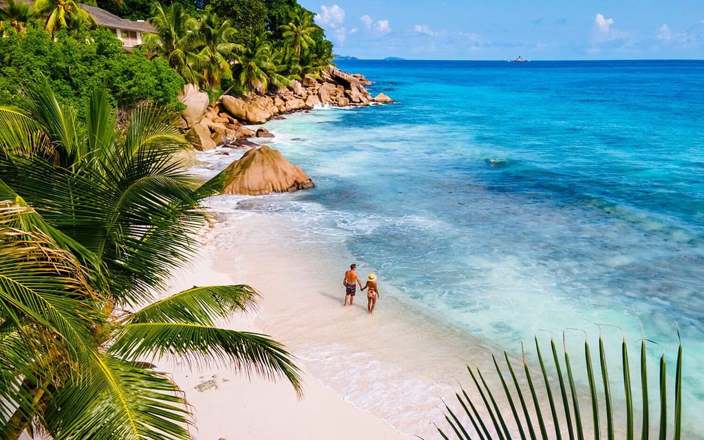 Anse Patates, La Digue Seychelles, una giovane coppia di uomini e donne su una spiaggia tropicale durante una vacanza di lusso alle Seychelles.  Spiaggia tropicale Anse Patates, La Digue Seychelles