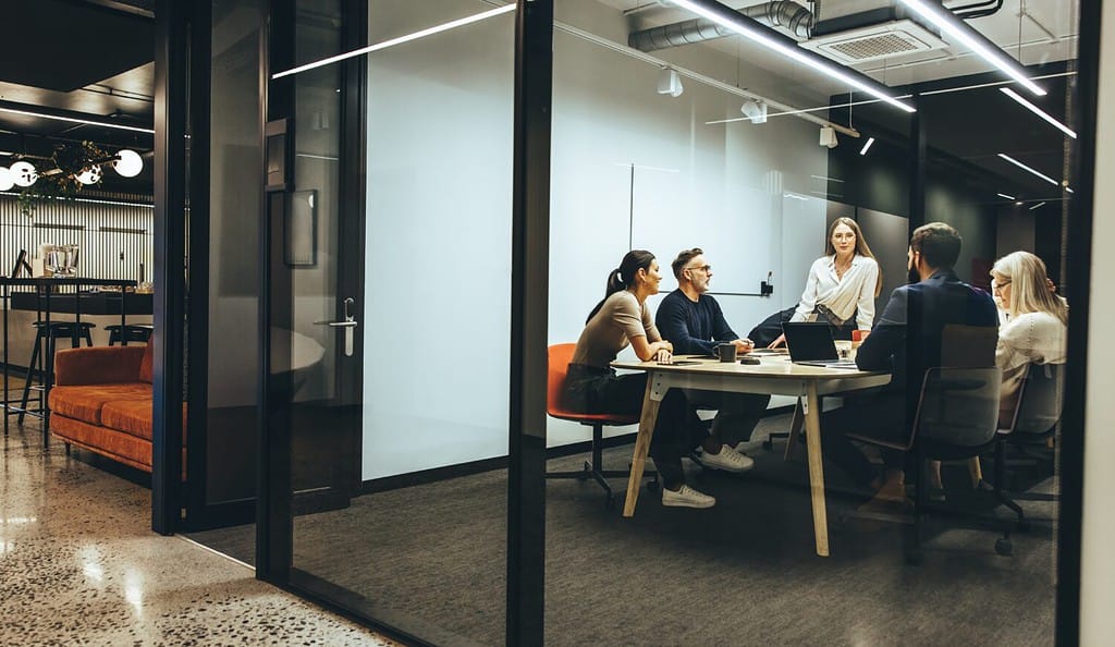 Team di uomini d'affari diversi che si riuniscono in una sala riunioni trasparente.  Gruppo di professionisti aziendali che discutono durante un briefing.  Colleghi che collaborano ad un nuovo progetto.