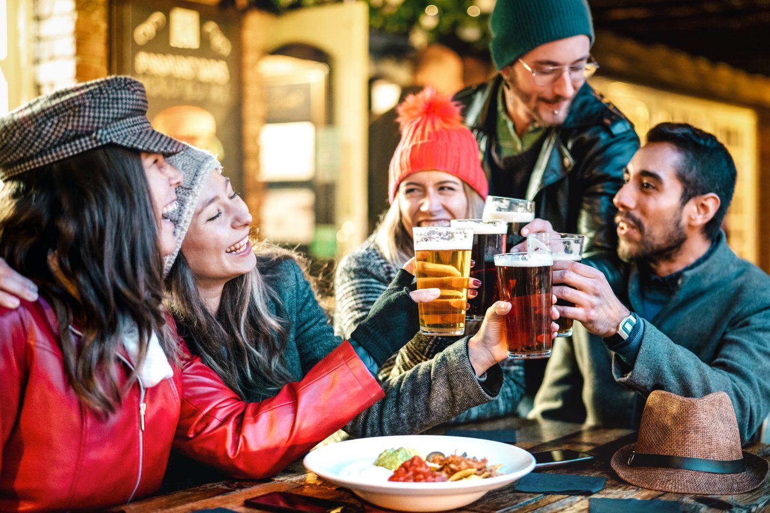 Amici multiculturali felici che bevono birra con nachos all'aperto di notte - Concetto di stile di vita di cibi e bevande per giovani che si divertono insieme all'aperto - Filtro caldo con focus sugli occhiali