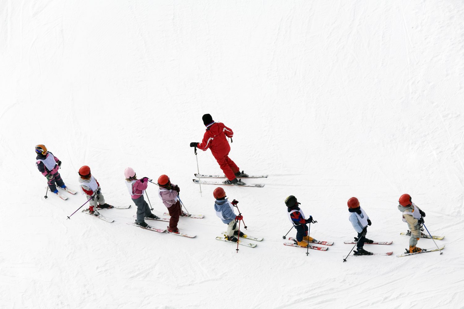 scena invernale: bambini che imparano a sciare e il loro maestro