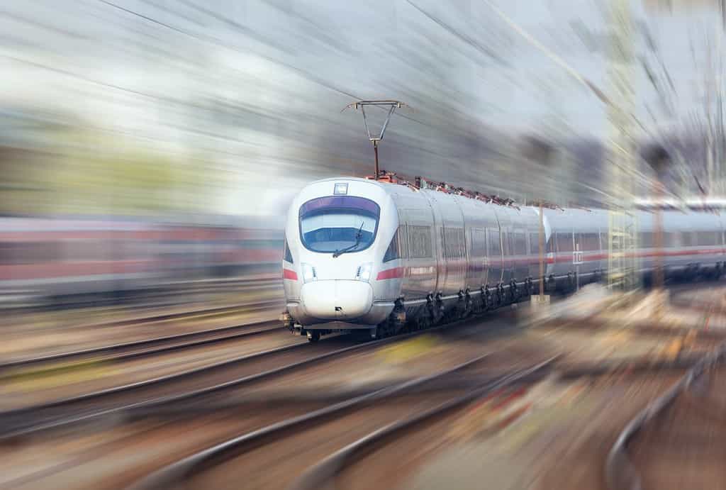 Stazione ferroviaria con un moderno treno ad alta velocità in movimento la sera a Norimberga, in Germania.  Treno bianco sulla ferrovia.  Effetto movimento