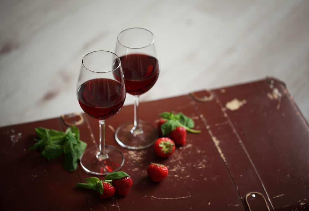 due bicchieri da vino con vino rosso decorati con fragola e menta