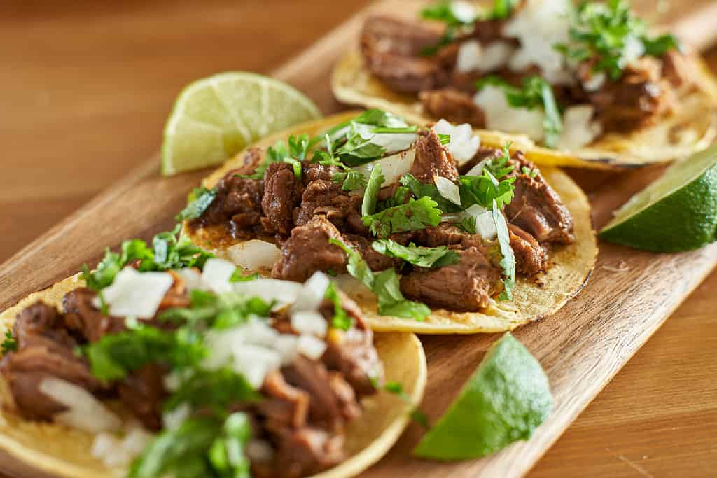 tre tacos messicani di carne asada in tortilla di mais con lime