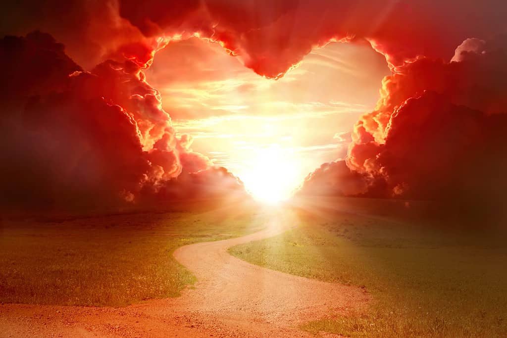 Cielo a forma di cuore rosso al tramonto.  Bellissimo paesaggio con strada e nuvole. Sfondo amore con spazio per la copia.  Strada per amare
