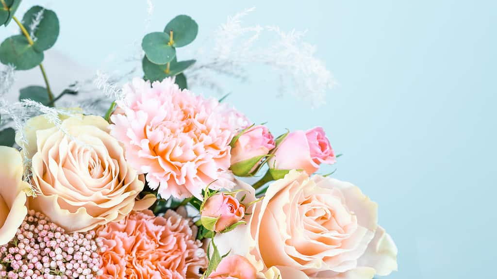 Bellissimo bouquet con garofani rosa e rose ravvicinate su sfondo blu.