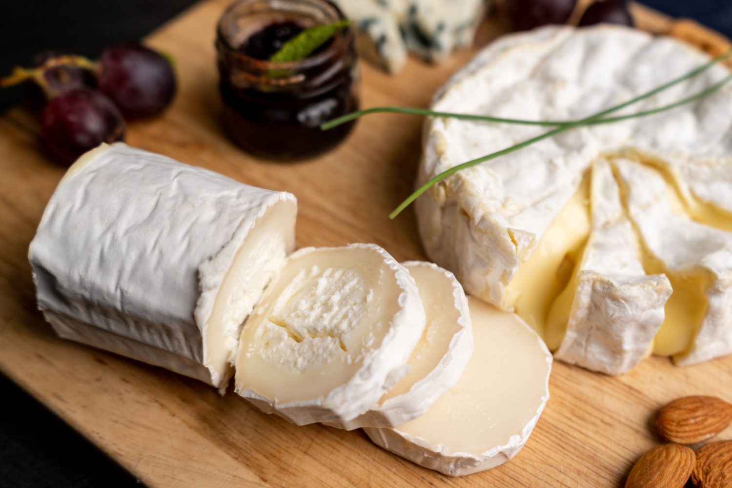 Formaggio di capra con altri formaggi e marmellata sullo sfondo su un tagliere