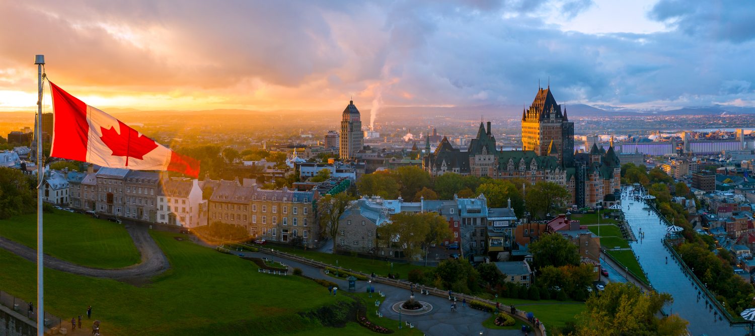 Una bandiera canadese sventola sulla Vecchia Quebec City al tramonto.  Vista panoramica aerea del drone di Quebec City, tra cui Chateau Frontenac e Differin Terrace.