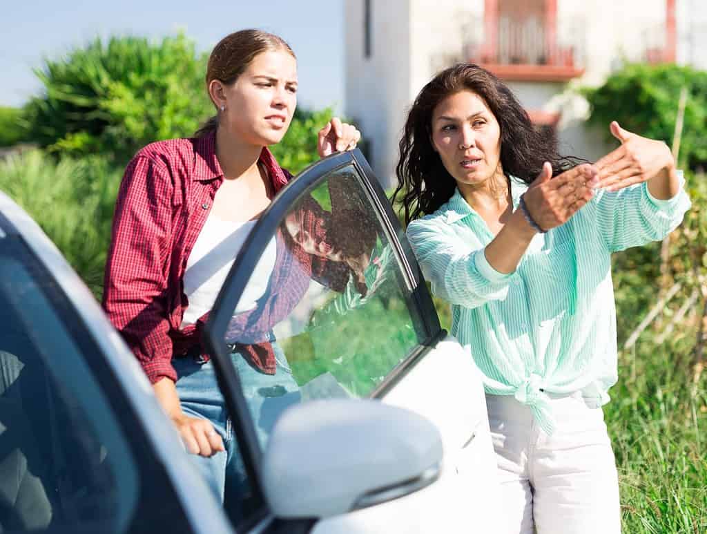 La giovane donna scese dall'auto e chiese la strada per raggiungere la destinazione.  Sta parlando con una donna asiatica che gesticola e le spiega come comportarsi.