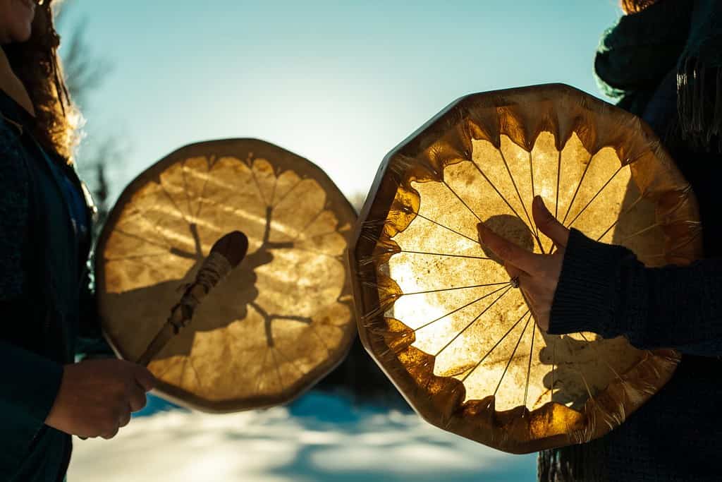 Donne che tengono e suonano i loro tamburi sacri all'aperto durante l'inverno