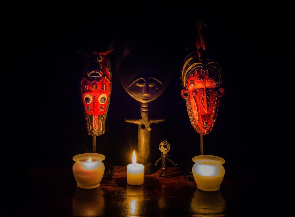 Rituale Voodoo - un'immagine stilizzata raffigurante un rituale voodoo.  Maschere africane, una dea della fertilità, una bambola voodoo e candele creano un'immagine sorprendente.