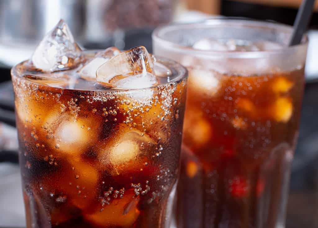 Cola con ghiaccio tritato nel bicchiere e ci sono gocce d'acqua intorno.  bevanda fresca nera fresca.
