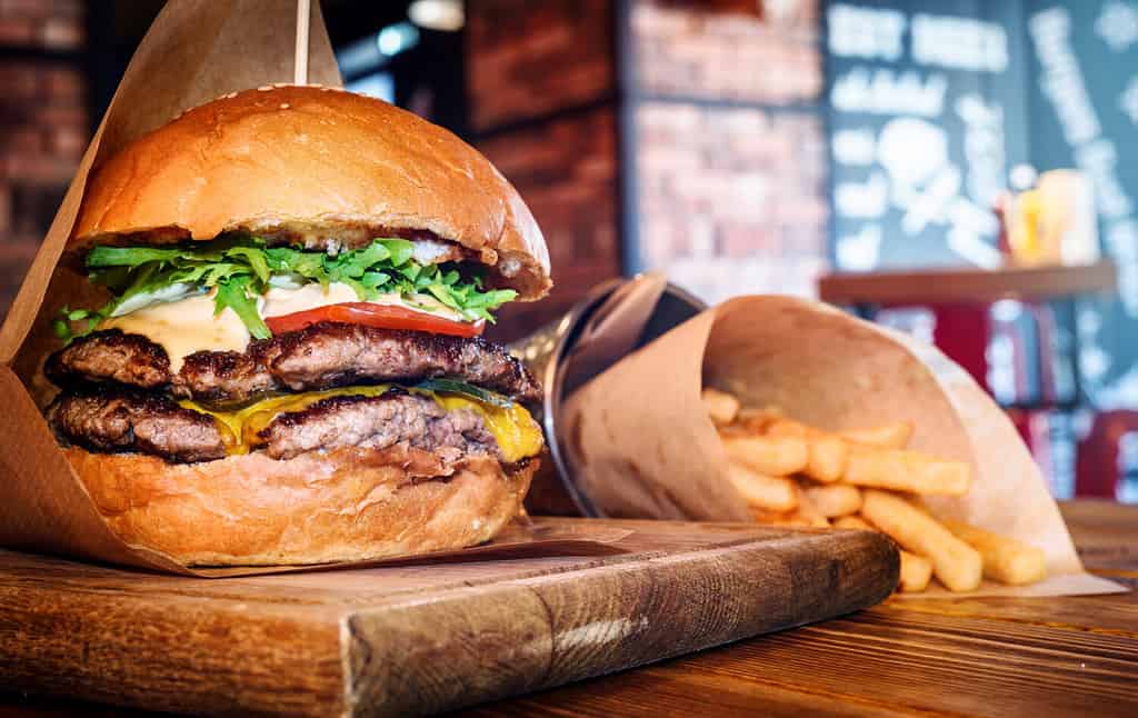 Hamburger fresco e gustoso e patatine fritte sul tavolo di legno