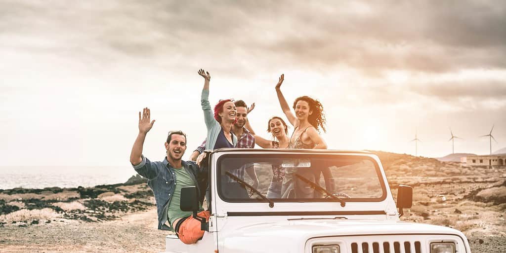 Amici turisti felici che fanno un'escursione nel deserto in un'auto 4x4 convertibile - Giovani che si divertono viaggiando insieme - Amicizia, tour, stile di vita giovanile e concetto di vacanza - Focus sui volti centrali