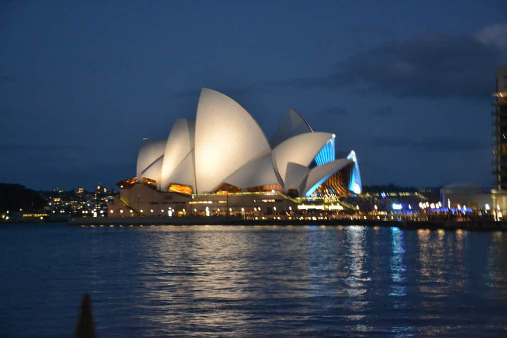 La Sydney Opera House si illumina di notte.  È un centro per le arti dello spettacolo multi-sede nel porto di Sydney e sito patrimonio mondiale dell'UNESCO.  Sydney, Nuovo Galles del Sud, Australia.