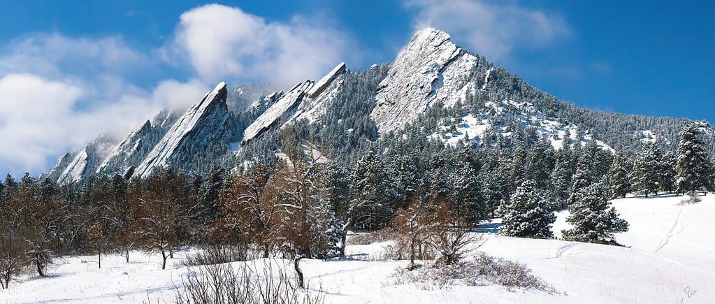 Boulder Colorado Flatirons glassato di neve che soffia contro un cielo blu chiaro.
