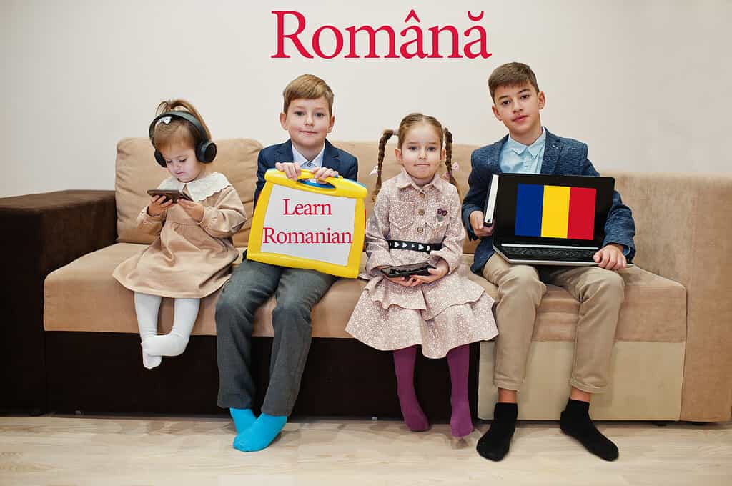 Quattro bambini mostrano l'iscrizione imparano il rumeno.  Concetto di apprendimento delle lingue straniere.  Romana.