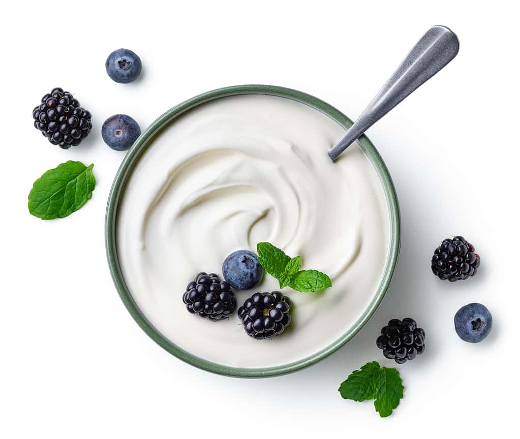 Ciotola verde di yogurt greco e frutti di bosco freschi isolati su sfondo bianco