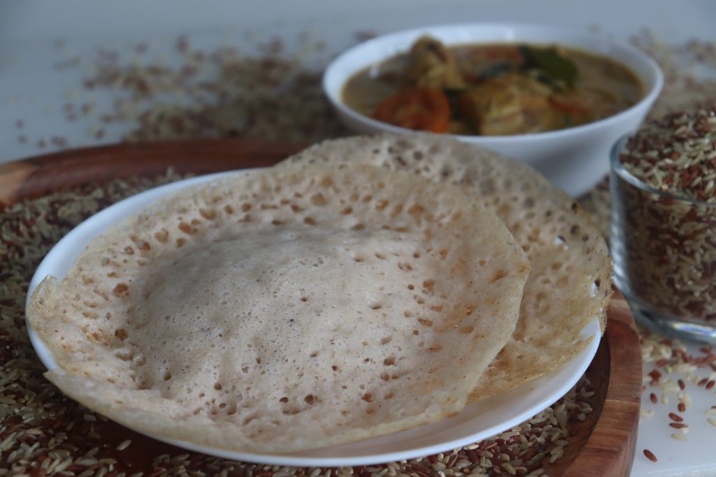 Appam di riso Rajamudi servito con pollo al curry del Kerala.