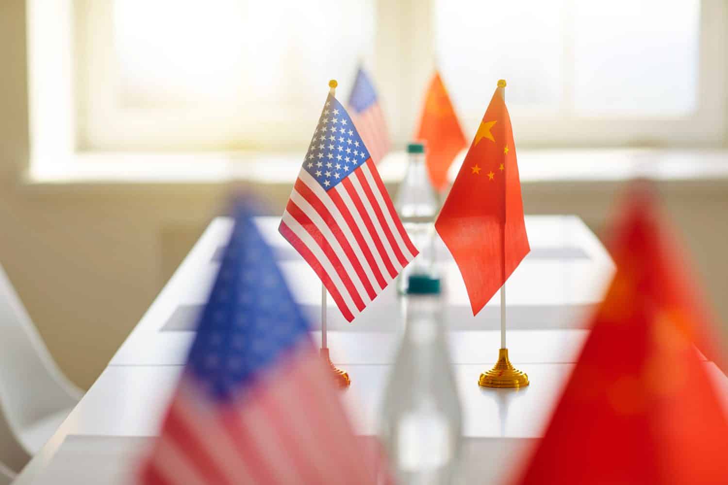 Negoziati tra Cina e America.  Primo piano delle bandiere della Cina e degli Stati Uniti sul tavolo durante una riunione per discutere delle relazioni commerciali.  Concetto di relazioni internazionali.  Messa a fuoco selettiva.