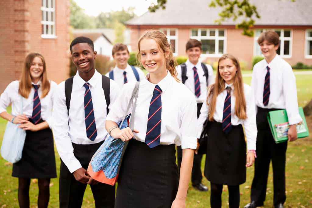 Ritratto di studenti adolescenti in uniforme all'esterno degli edifici scolastici
