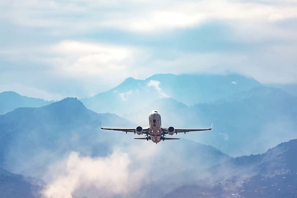 Foto d'archivio del concetto di viaggio del volo aereo.  L'aereo vola sopra un'incredibile montagna nebbiosa blu