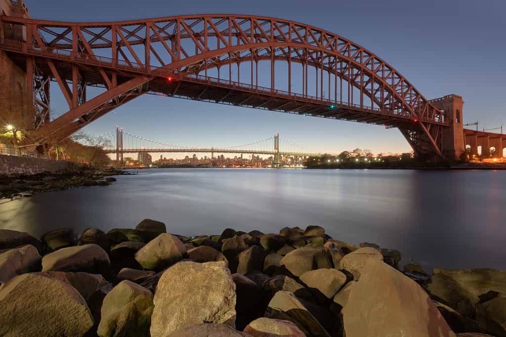 New York, New York, Stati Uniti d'America al Hell Gate Bridge al tramonto sull'East River al crepuscolo.