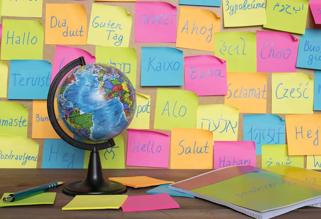 Studiare il concetto di lingue, un globo e note di colore con la parola Ciao in diverse lingue.