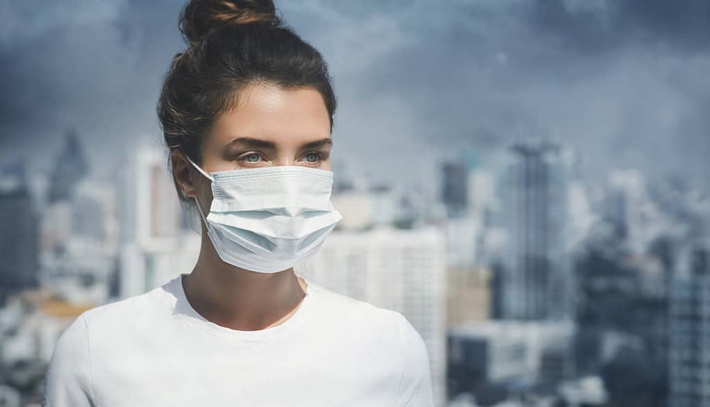 Donna che indossa una maschera facciale a causa dell'inquinamento atmosferico in città