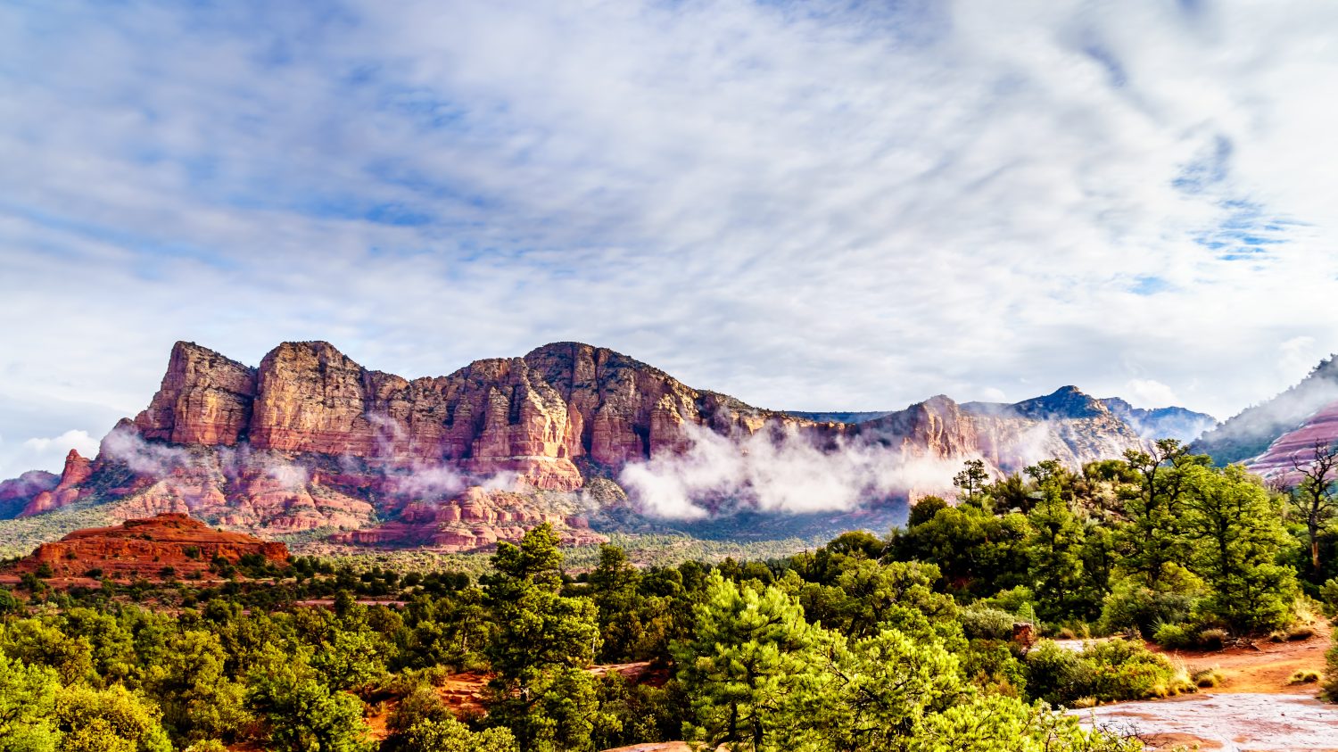 Nuvole che circondano Lee Mountain, Munds Mountain e altre montagne di roccia rossa che circondano la città di Sedona, nel nord dell'Arizona, nella foresta nazionale di Coconino, Stati Uniti d'America