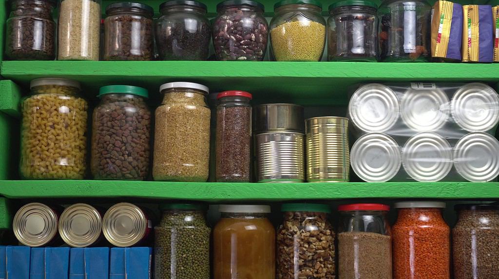 Scaffale per la conservazione delle scorte alimentari.  Dispensa domestica fornita pronta per la quarantena e l'autoisolamento del coronavirus.  Alimenti, bevande, provviste per lunghe conservazioni.  Fagioli secchi, riso, pasta, noci, semi, prodotti in scatola e verdure