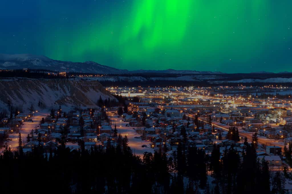 Forte tempesta di aurora boreale (Aurora boreale) nel cielo notturno sopra il centro di Whitehorse, capitale del territorio dello Yukon, Canada, in inverno.