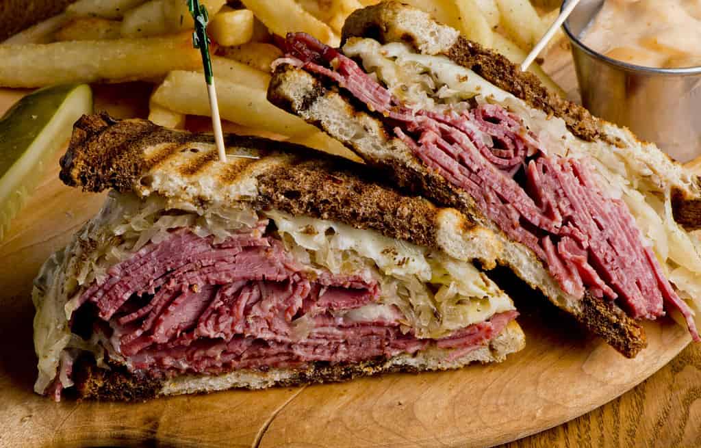 Panino Ruben.  Classico panino americano della tradizione.  Pastrami e carne in scatola su pane di segale grigliato, formaggio svizzero fuso, crauti, conditi con salsa mille isolana e patatine fritte.