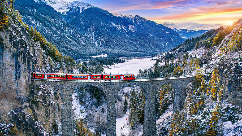 Veduta aerea del treno che passa attraverso la famosa montagna di Filisur, Svizzera.  Patrimonio mondiale del viadotto Landwasser con il treno espresso nello scenario invernale innevato delle Alpi svizzere.