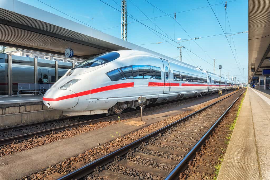 Treno bianco ad alta velocità sulla stazione ferroviaria al tramonto.  Norimberga, Germania.  Moderno treno interurbano sulla piattaforma ferroviaria.  Industriale.  Incredibile treno passeggeri sulla ferrovia.  Trasporti.  Europa