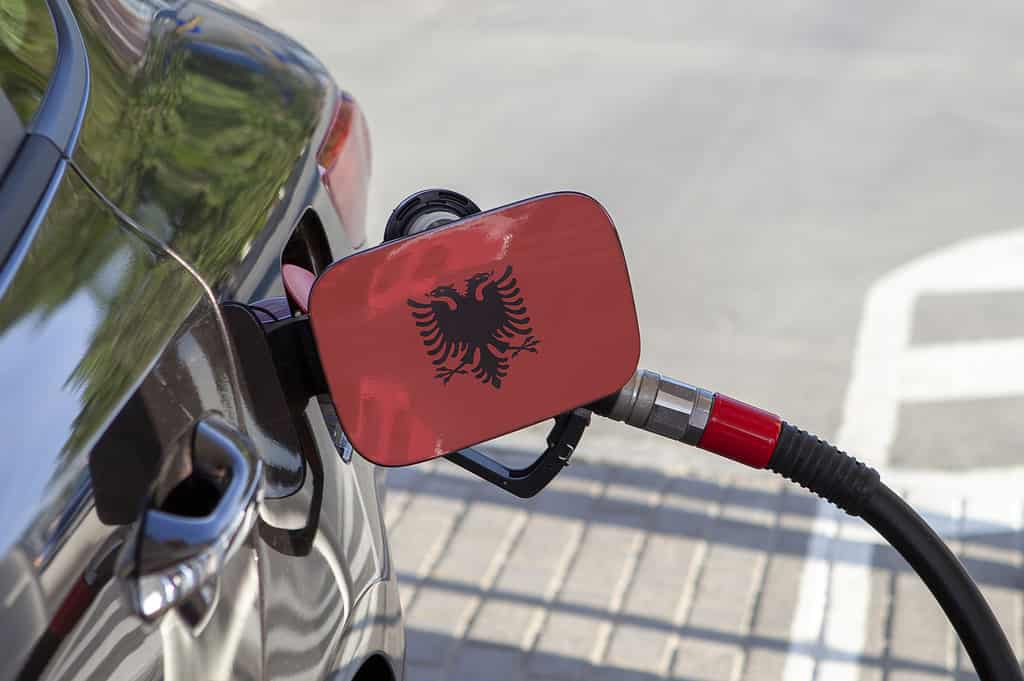 Bandiera dell'Albania sullo sportellino del serbatoio del carburante dell'auto.  Rifornimento di auto con pompa di benzina in una stazione di servizio.  Stazione di rifornimento.  Benzina e prodotti petroliferi.  Avvicinamento.