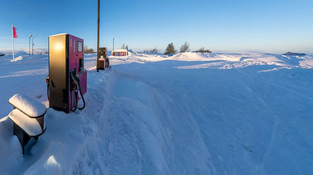 Pompa di benzina e diesel circondata da neve e illuminata dalla luce del sole mattutino in una stazione di servizio in Islanda dopo una forte nevicata