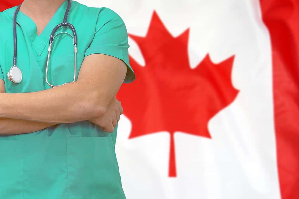 Chirurgo maschio o medico con stetoscopio sullo sfondo della bandiera del Canada.  Assistenza sanitaria e concetto medico.  Concetto di chirurgia in Canada.