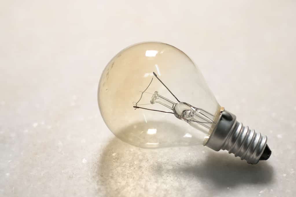 Una piccola lampadina o lampada a incandescenza su superficie dura bianca