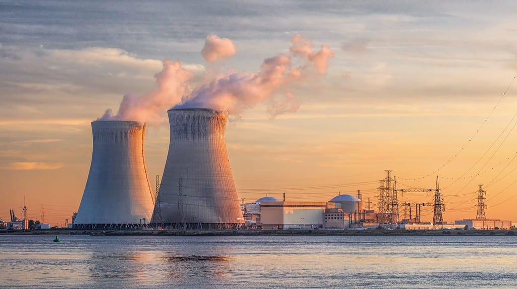 Scena nel tardo pomeriggio con vista sulla riva del fiume con il reattore nucleare Doel, porto di Anversa, Belgio.