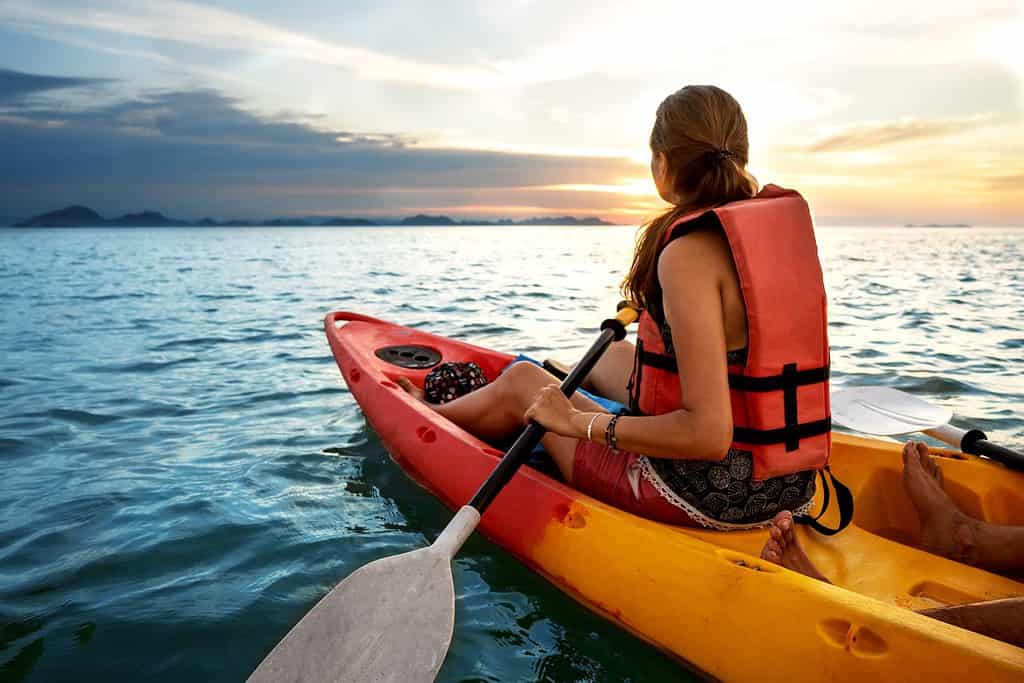 Coppia in kayak insieme.  Bella giovane coppia in kayak sul lago insieme e sorridente al tramonto