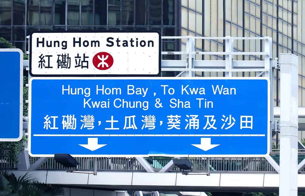 Grandi segnali stradali in inglese e cinese sull'autostrada di Hong Kong mostrano le indicazioni per diverse parti della città
