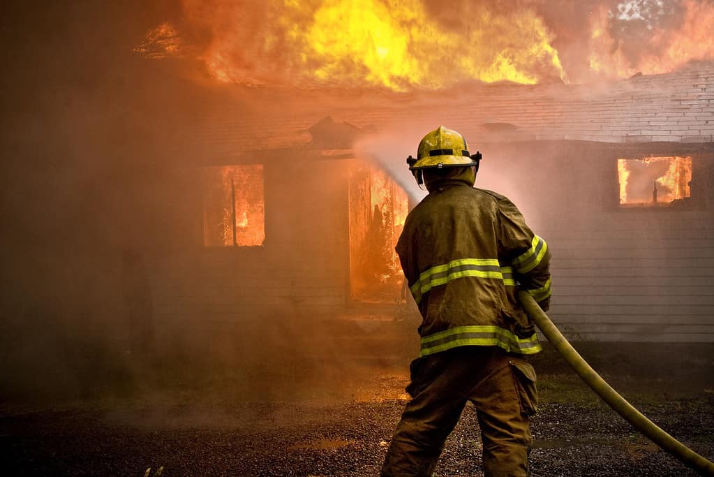 Vigile del fuoco che spruzza acqua durante un incendio in una casa