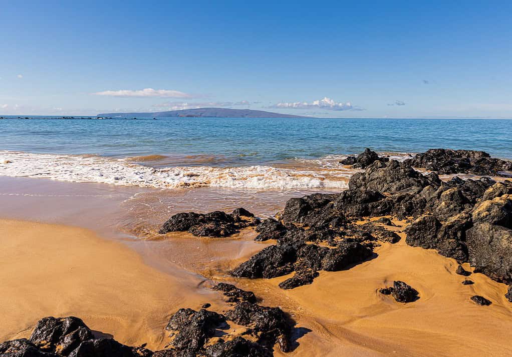 Onde che si riversano su massi di lava sulla spiaggia di Keawakapu, Maui, Hawaii, Stati Uniti