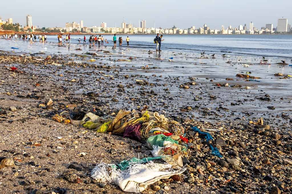 L'estesa Chowpatty Beach a Bombay, in India, con le persone, tutta la spazzatura e gli edifici in lontananza.