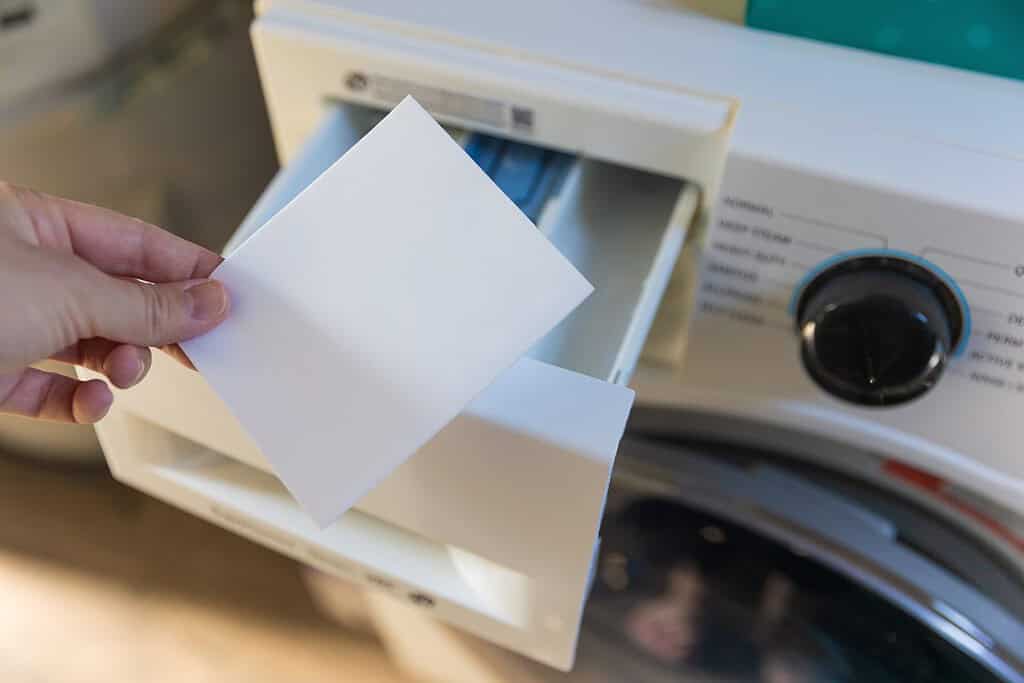 Donna che mette un lenzuolo nella lavatrice